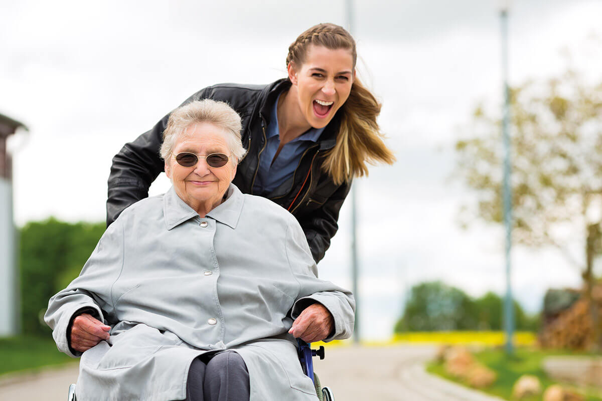 Frau im Rollstuhl mit Pflegerin